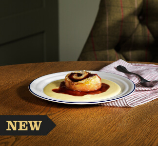 Whitbread Inns Jam Roly Poly with custard and red jam on a plate.
