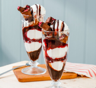 Whitbread Inns Vegan Black Forest Sundae with cherry and chocolate sauce in glasses on a table.